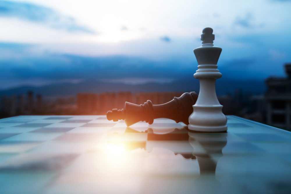 Chess white king standing and black king falling.