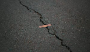 Small band-aid on a large crack on pavement