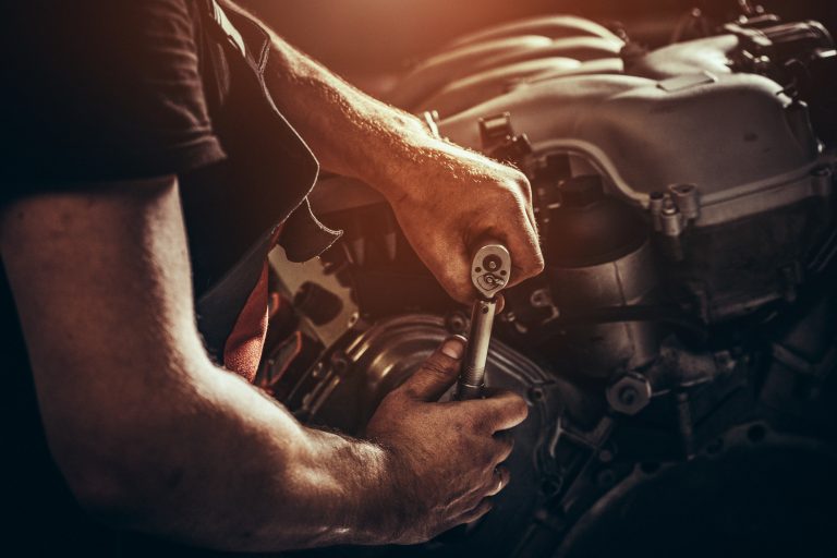 The hands of a mechanic working on an engine