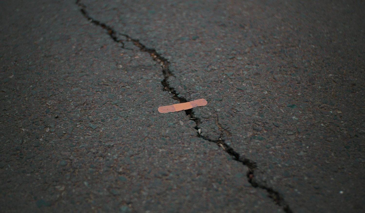 Small band-aid on a large crack on pavement
